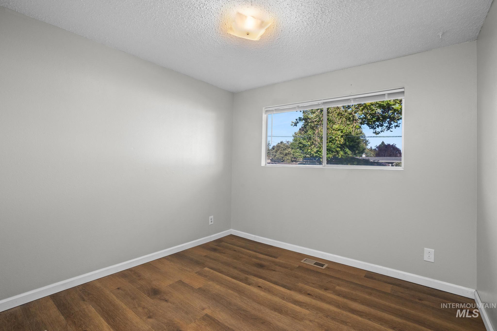 2037 South Curtis Road Boise, ID 83705 - Photo 16 of 32 Wood-finish flooring, light gray wall paint, and a window with a natural backdrop
