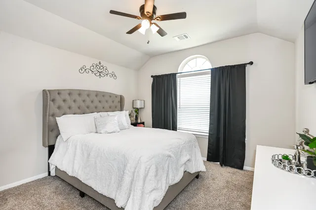 a bedroom with a large bed and ceiling fan