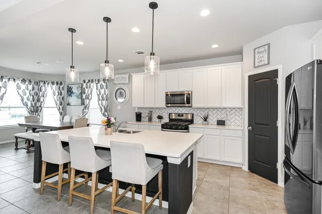 a kitchen with stainless steel appliances kitchen island granite countertop a table chairs microwave and refrigerator