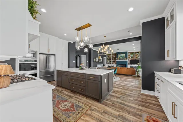 a kitchen with stainless steel appliances kitchen island granite countertop a sink stove and refrigerator