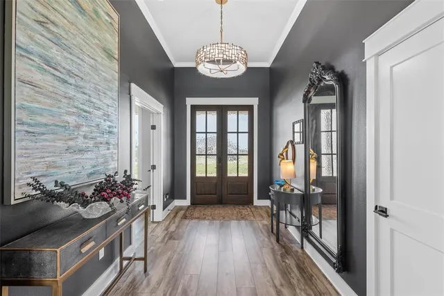 a view of a hallway with wooden floor and a chandelier
