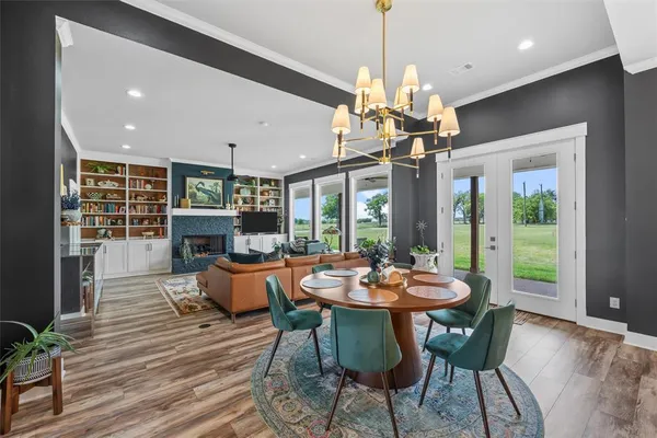a dining room with wooden floor a chandelier a wooden table and chairs