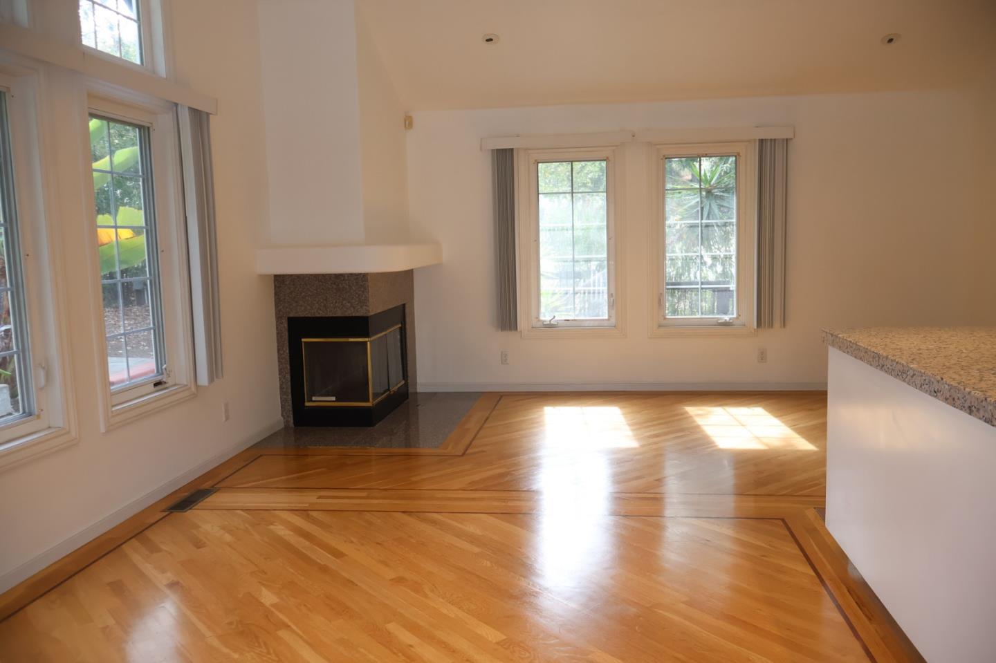 2360 Woodside Road, Unit A Woodside, CA 94062 - Photo 9 of 27 an empty room with wooden floor fireplace and windows