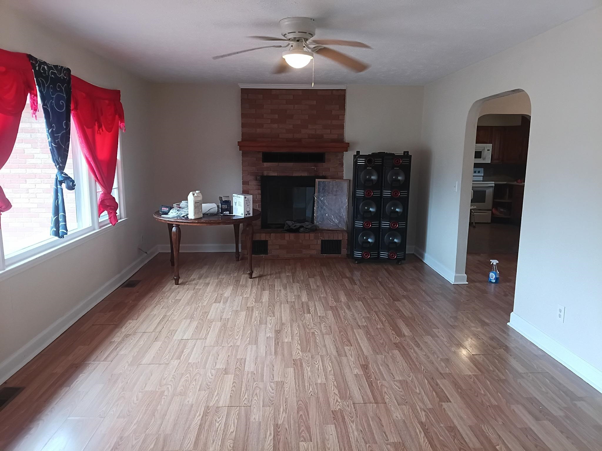 4625 Graham Street Loris, SC 29569 - Photo 11 of 11 Living room with light wood-type flooring, a brick fireplace, arched walkways, and a ceiling fan