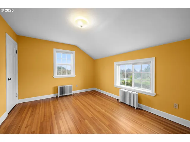a view of an empty room with a window and wooden floor