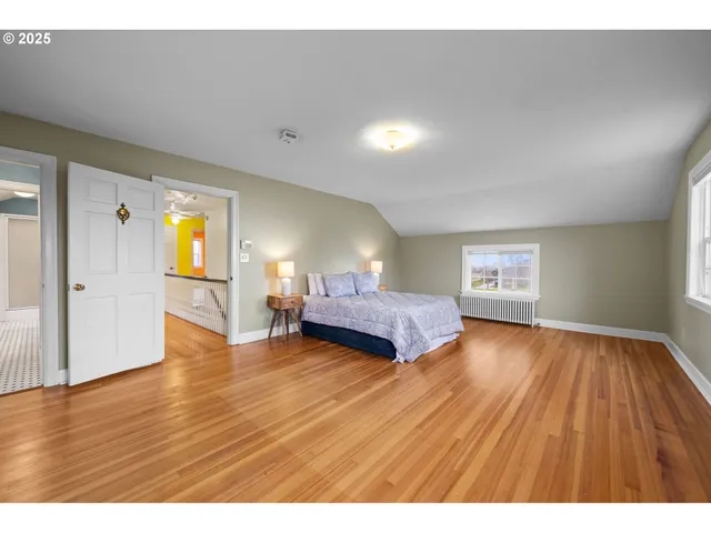 a spacious bedroom with a bed and wooden floor
