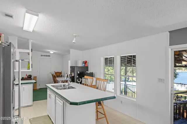 a kitchen with kitchen island a stove a refrigerator a sink dishwasher with a dining table and chairs