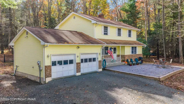 a view of a white house with a small yard and large trees