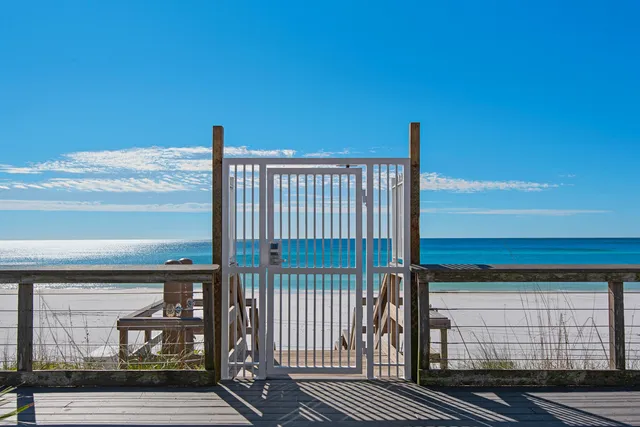 a view of a patio with couches table and chairs under an umbrella with a small yard