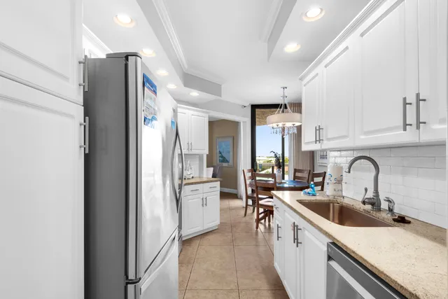 a kitchen with stainless steel appliances granite countertop white cabinets a refrigerator a stove a sink and dishwasher with wooden floor