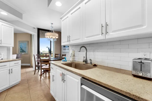 a living room with dining table a window stainless steel appliances and a chandelier