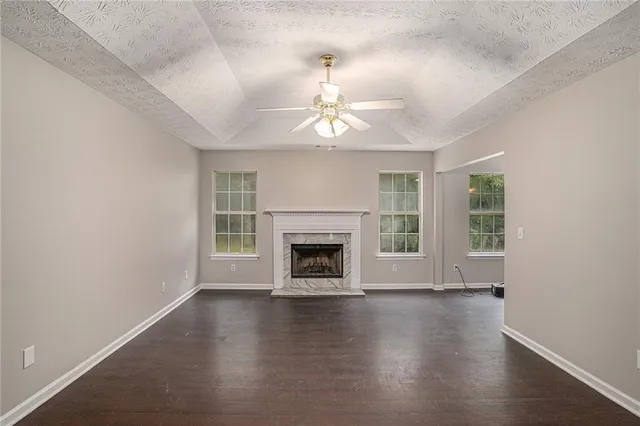 an empty room with wooden floor fireplace and windows