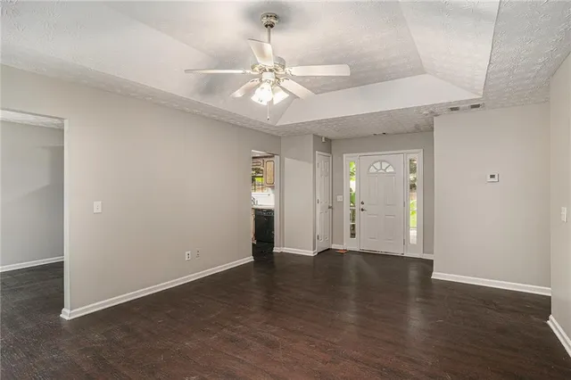 an empty room with wooden floor fan and windows
