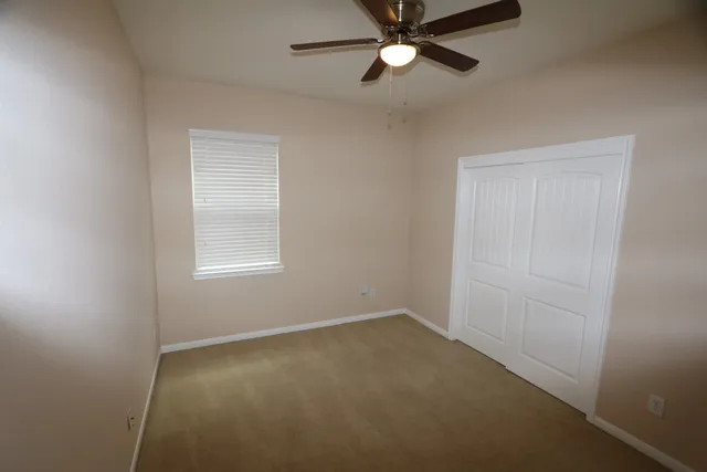 an empty room with a window and a fan