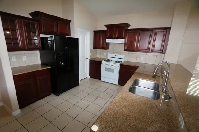 a kitchen with stainless steel appliances granite countertop a refrigerator stove top oven a sink and dishwasher