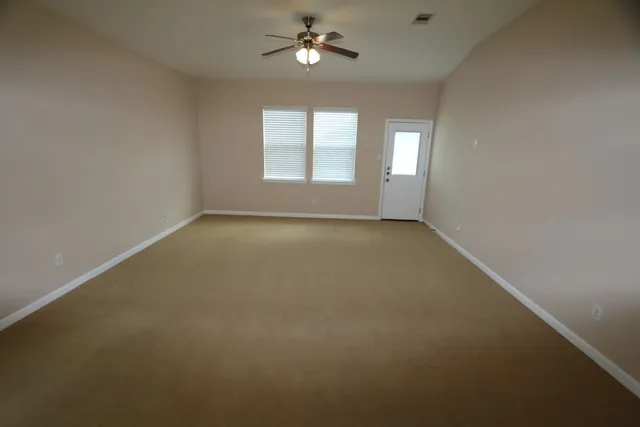 an empty room with windows and fan