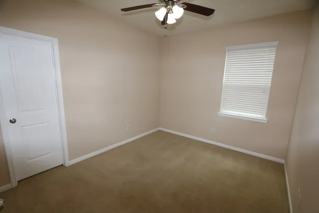 an empty room with a window and a fan