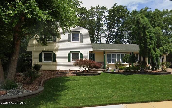 a front view of a house with a garden and trees