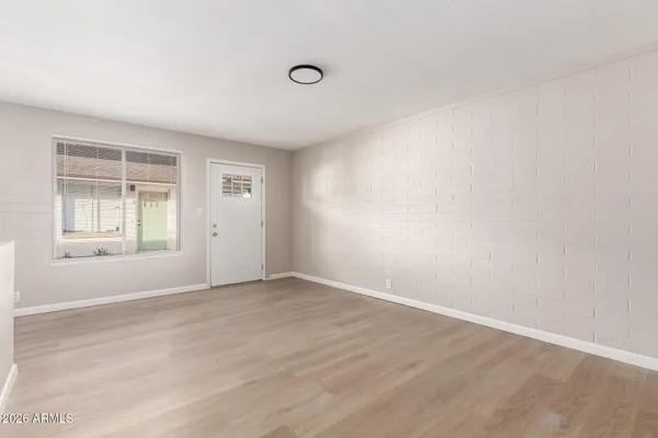 an empty room with wooden floor and windows