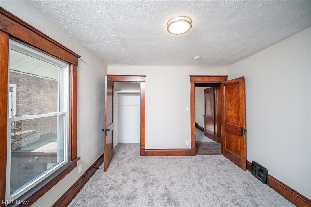 809 Wales Road Northeast Massillon, OH 44646 - Photo 11 of 15 Unfurnished bedroom with light carpet, a textured ceiling, and a closet