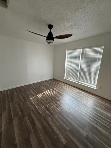 an empty room with wooden floor fan and windows