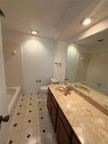 a spacious bathroom with a granite countertop sink a mirror and a bathtub