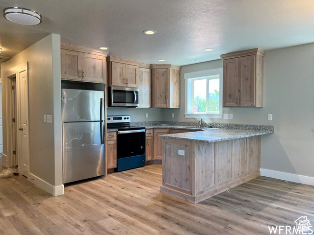 702 North 100 West Logan, UT 84321 - Photo 29 of 58 Kitchen with a peninsula, stainless steel appliances, light wood-style floors, and baseboards