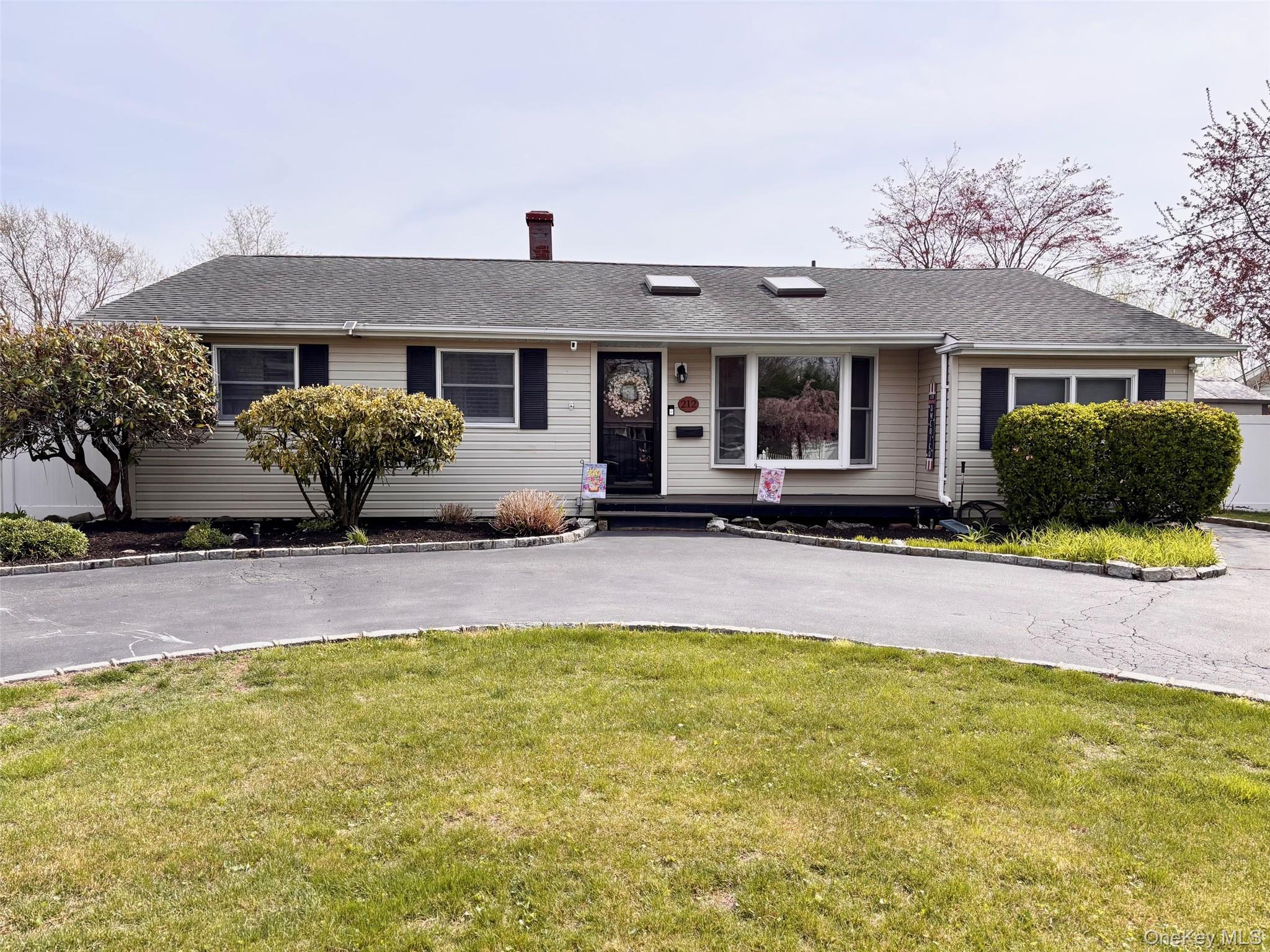 Ranch-style exterior featuring light-colored siding, a dark asphalt shingle roof, and a bay window