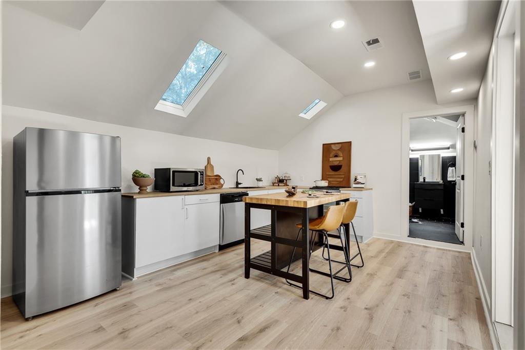 901 Argonne Avenue Northeast, Unit B Atlanta, GA 30309 - Photo 9 of 30 a kitchen with a refrigerator a microwave oven a sink and a dining table with wooden floor