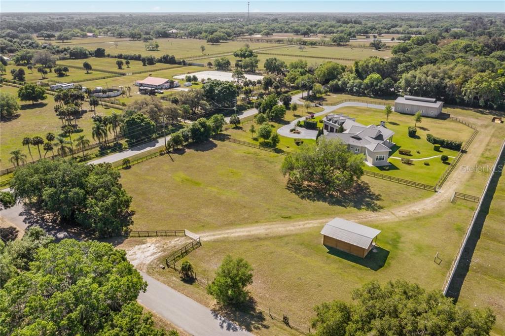 Aerial of 4.79 acres with the 3 stall loafing shed in the foreground and the 2600 SF Storage building in the rear with the luxurious 4144 SF residence.
