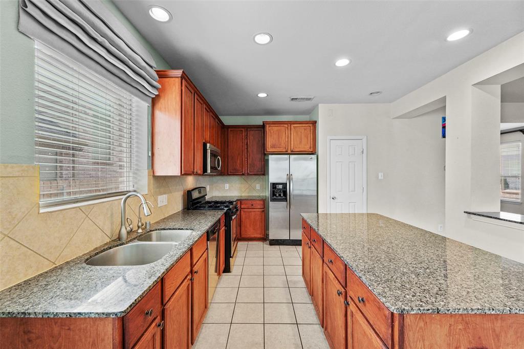 2405 Reston Drive McKinney, TX 75072 - Photo 12 of 38 Kitchen with stainless steel appliances, light stone countertops, backsplash, recessed lighting, and light tile patterned flooring