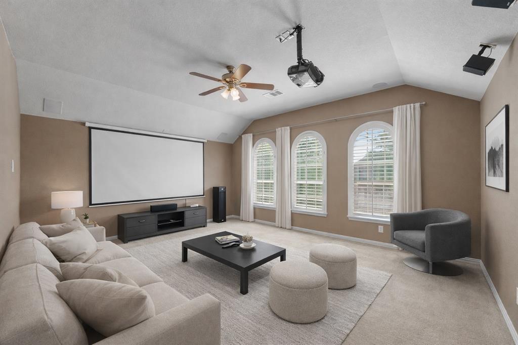 2405 Reston Drive McKinney, TX 75072 - Photo 20 of 38 Spacious entertainment area featuring a projector, large screen, and three arched windows with blinds