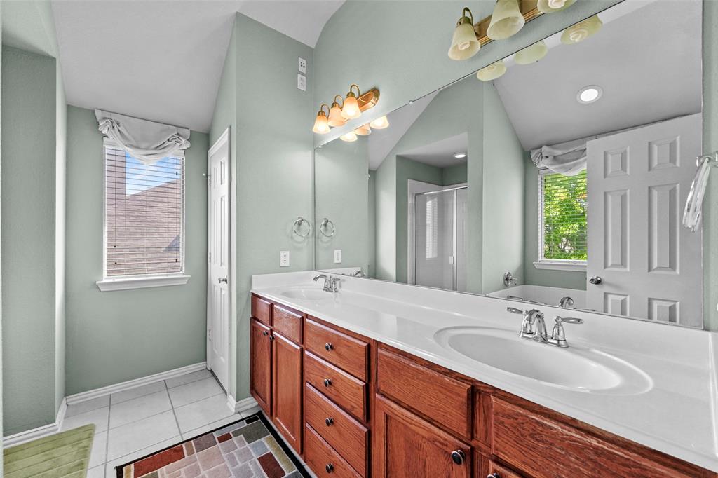 2405 Reston Drive McKinney, TX 75072 - Photo 26 of 38 Full bathroom featuring double vanity, a stall shower, light tile patterned floors, a bath, and lofted ceiling