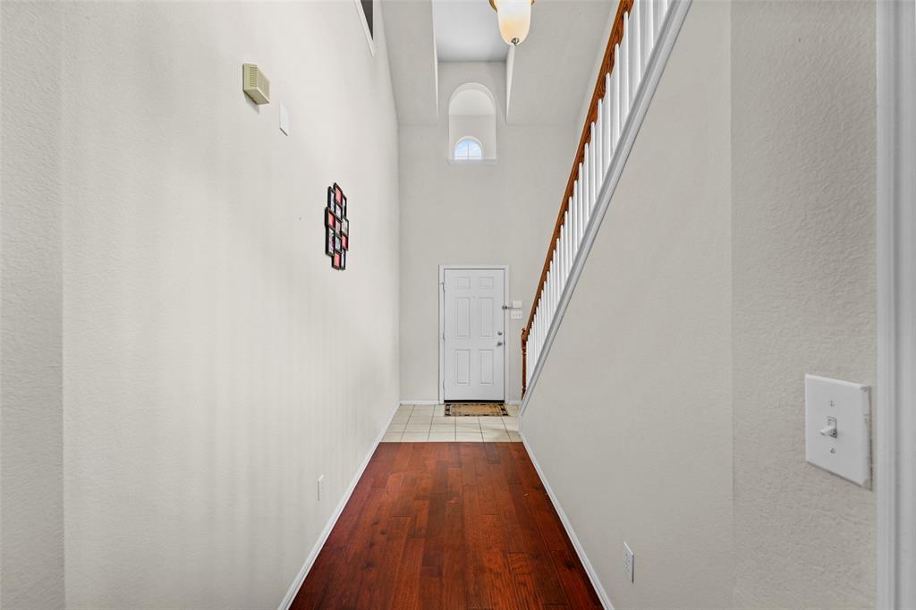 2405 Reston Drive McKinney, TX 75072 - Photo 6 of 38 Hallway with a high ceiling, light wood finished floors, and a textured wall