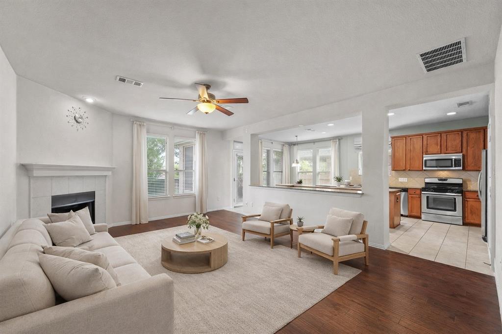 2405 Reston Drive McKinney, TX 75072 - Photo 8 of 38 Spacious living area featuring hardwood floors, a white tile fireplace, and large windows providing natural light