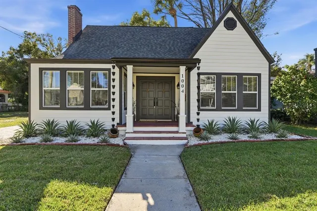 a front view of a house with a yard and potted plants
