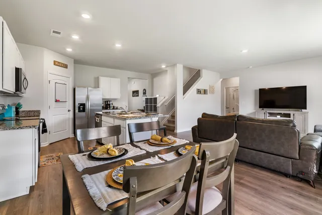 a kitchen with a dining table chairs and a refrigerator