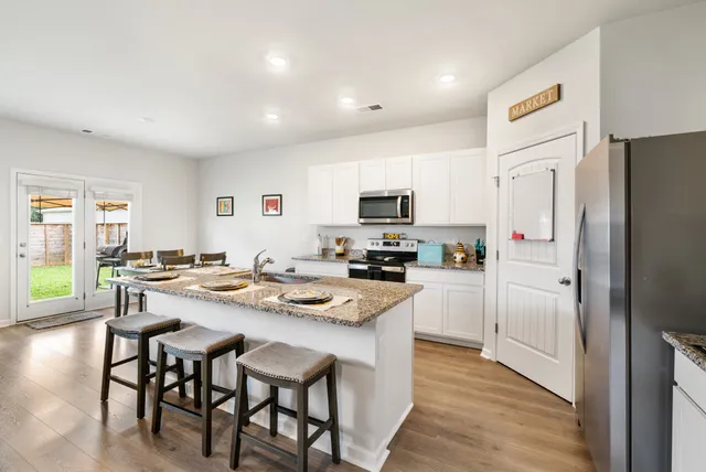 a kitchen with a sink a stove and chairs with wooden floor