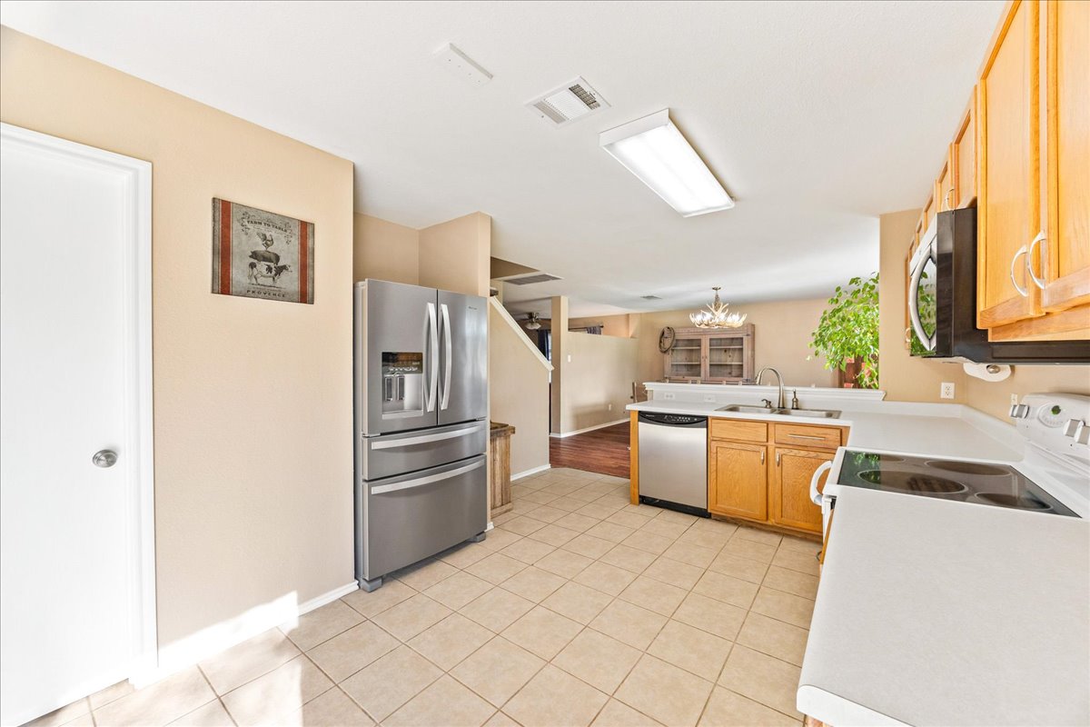 116 Devon's Cove Buda, TX 78610 - Photo 23 of 38 Kitchen featuring stainless steel appliances, light countertops, a peninsula, and hanging lights