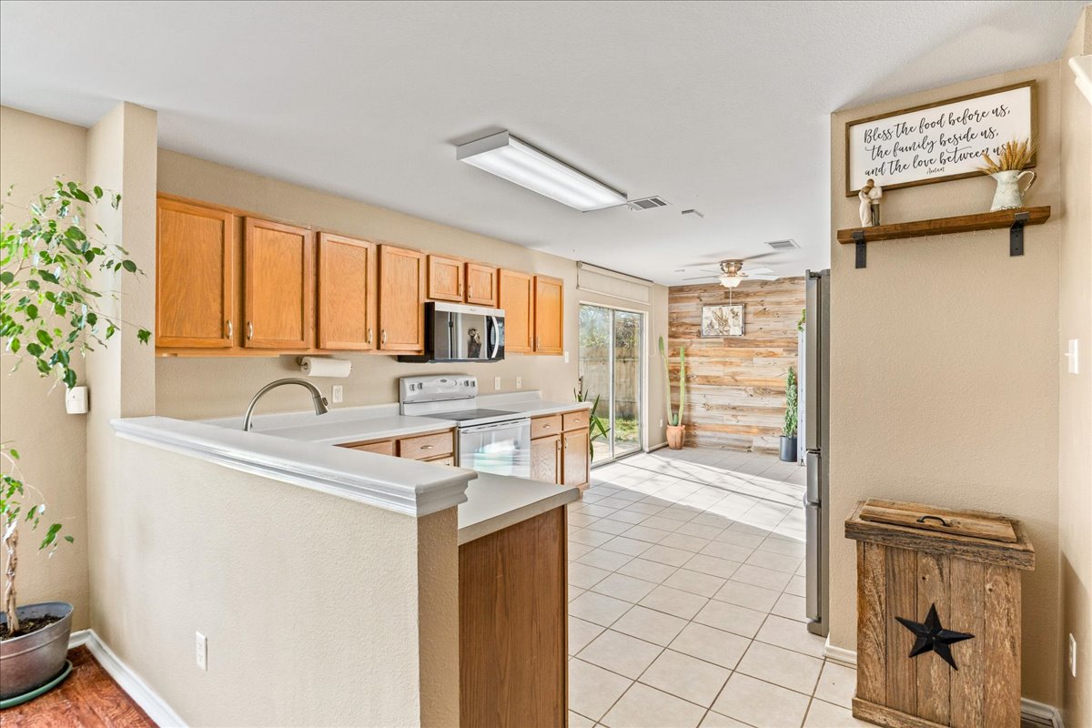 116 Devon's Cove Buda, TX 78610 - Photo 25 of 38 Kitchen featuring stainless steel appliances, ceiling fan, light countertops, light tile patterned floors, and light wood finish cabinets