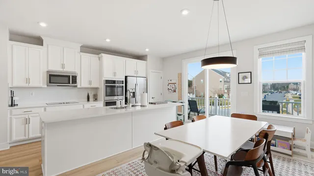 a large kitchen with kitchen island a white table and chairs