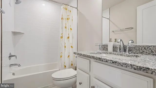 a bathroom with a granite countertop sink a toilet and shower