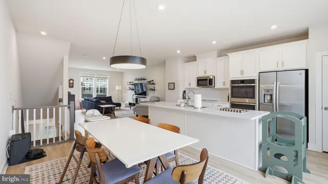 a kitchen with stainless steel appliances a dining table chairs stove refrigerator and cabinets