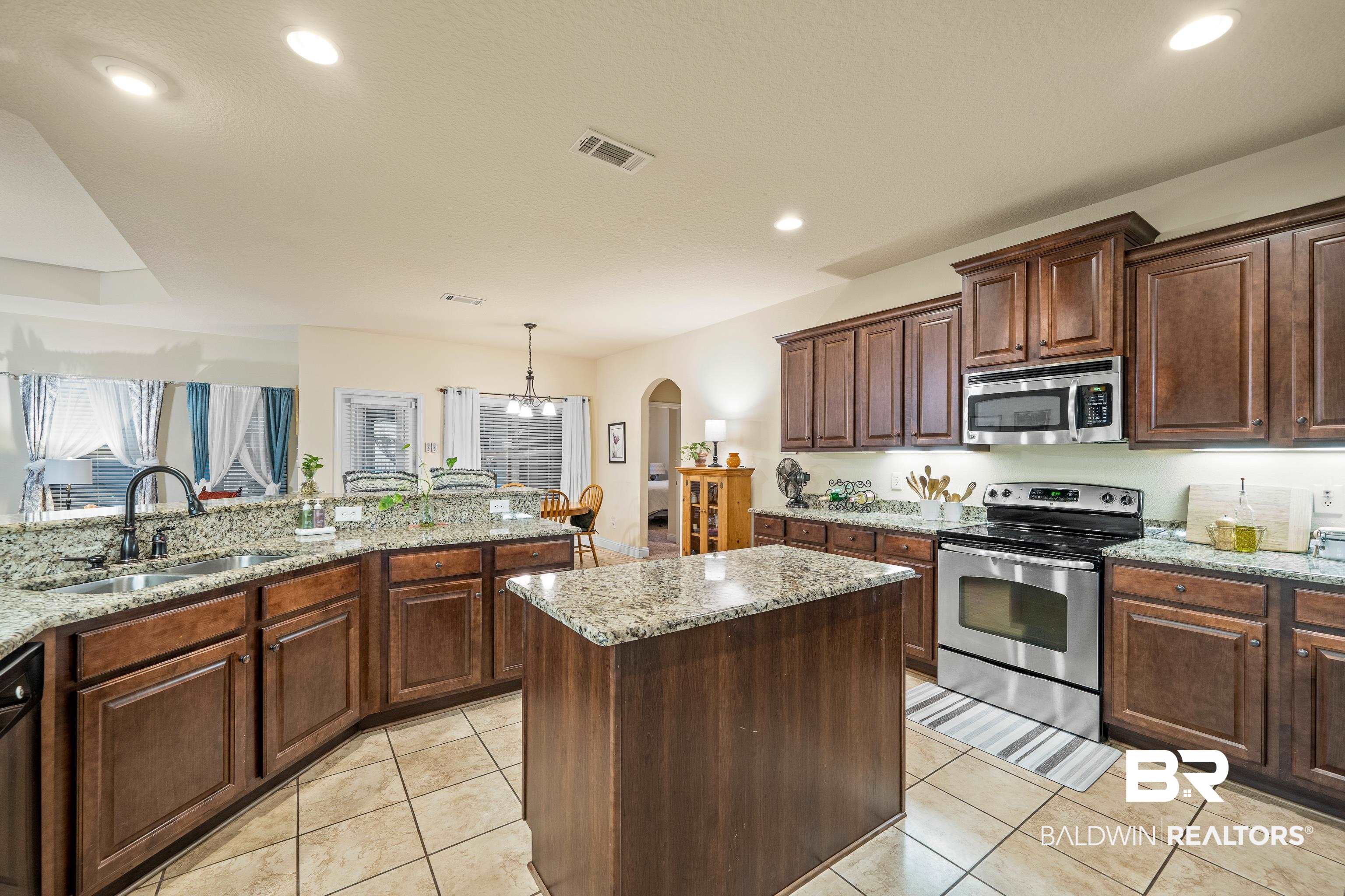 9115 Krystal Ridge Court Daphne, AL 36526 - Photo 12 of 39 Kitchen featuring sink, appliances with stainless steel finishes, decorative light fixtures, a kitchen island, and light stone counters