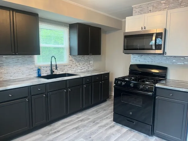a kitchen with stainless steel appliances a stove a sink and a microwave