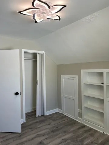 a view of an empty room with a ceiling fan wooden floor and window
