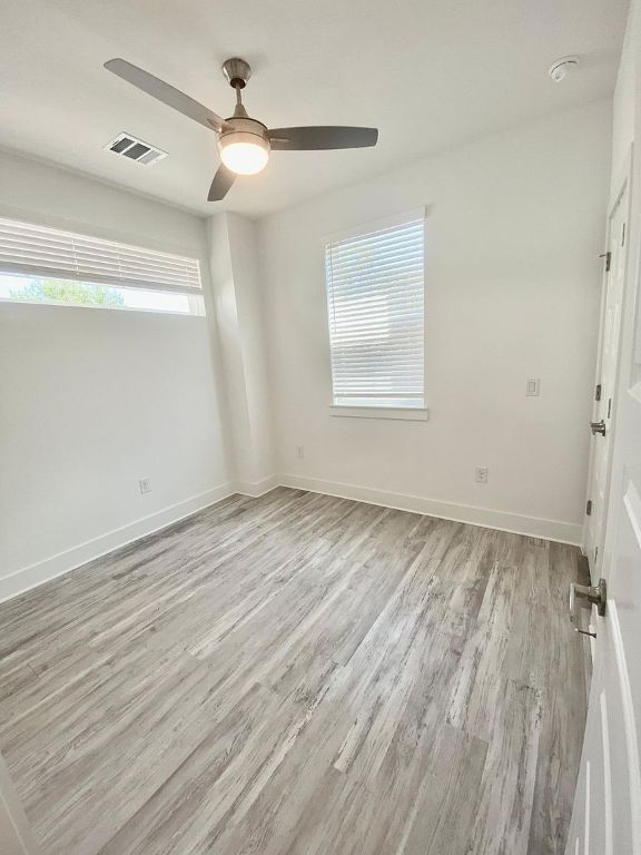 6809 Montana Street, Unit 2 Austin, TX 78741 - Photo 21 of 29 an empty room with wooden floor chandelier fan and windows