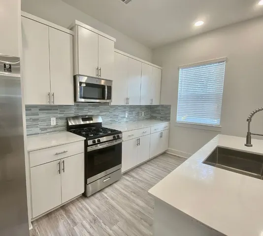 a kitchen with stainless steel appliances granite countertop a sink a stove a microwave and wooden cabinets