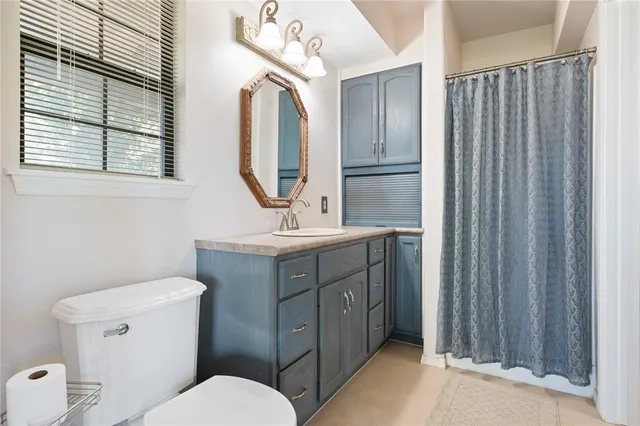 a bathroom with a toilet a sink a mirror a vanity and window