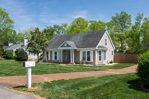 a front view of a house with a yard and trees